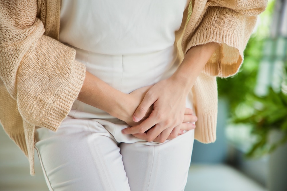 Close up of a woman clutching her groin area in pain from a urinary tract infection, in need of treatment.